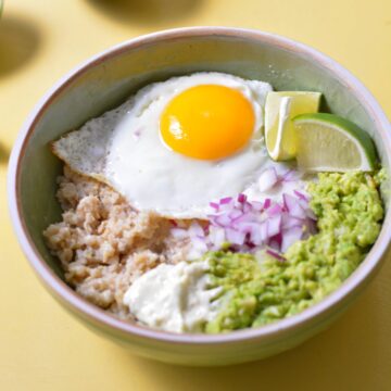 Oatmeal with an egg, avocado, red onion, and queso on top.